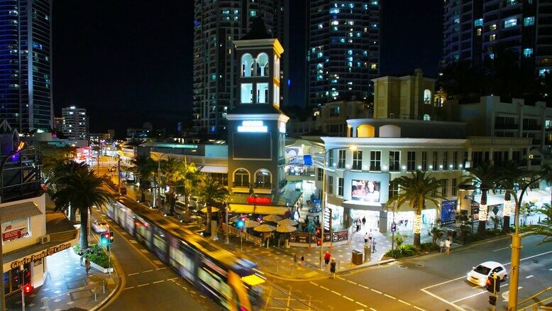surfers paradise accommodation apartments near cavill mall at night with tram, dining precinct, and high-rise skyline